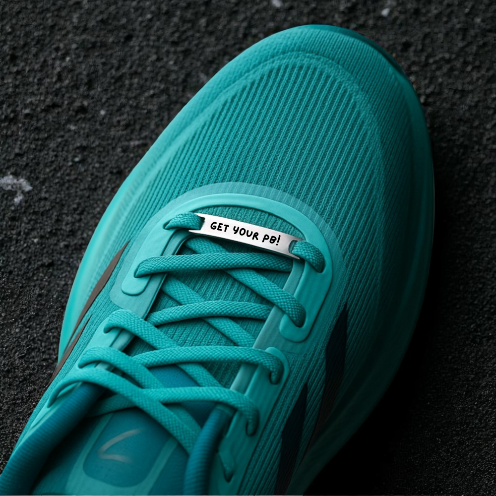 Teal running shoe with a shoelace clip on a dark surface