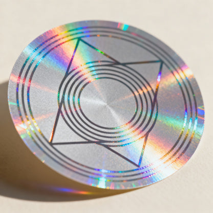 Holographic circular sticker with geometric design on a beige background

