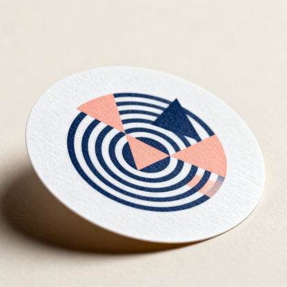 Round coaster with blue and pink design on a beige background