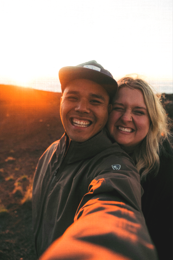 Two people taking a selfie with a sunset in the background