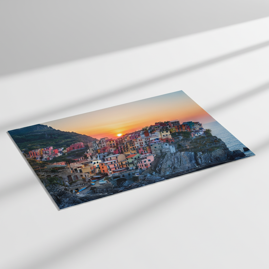 Framed artwork of a coastal village at sunset on a white surface